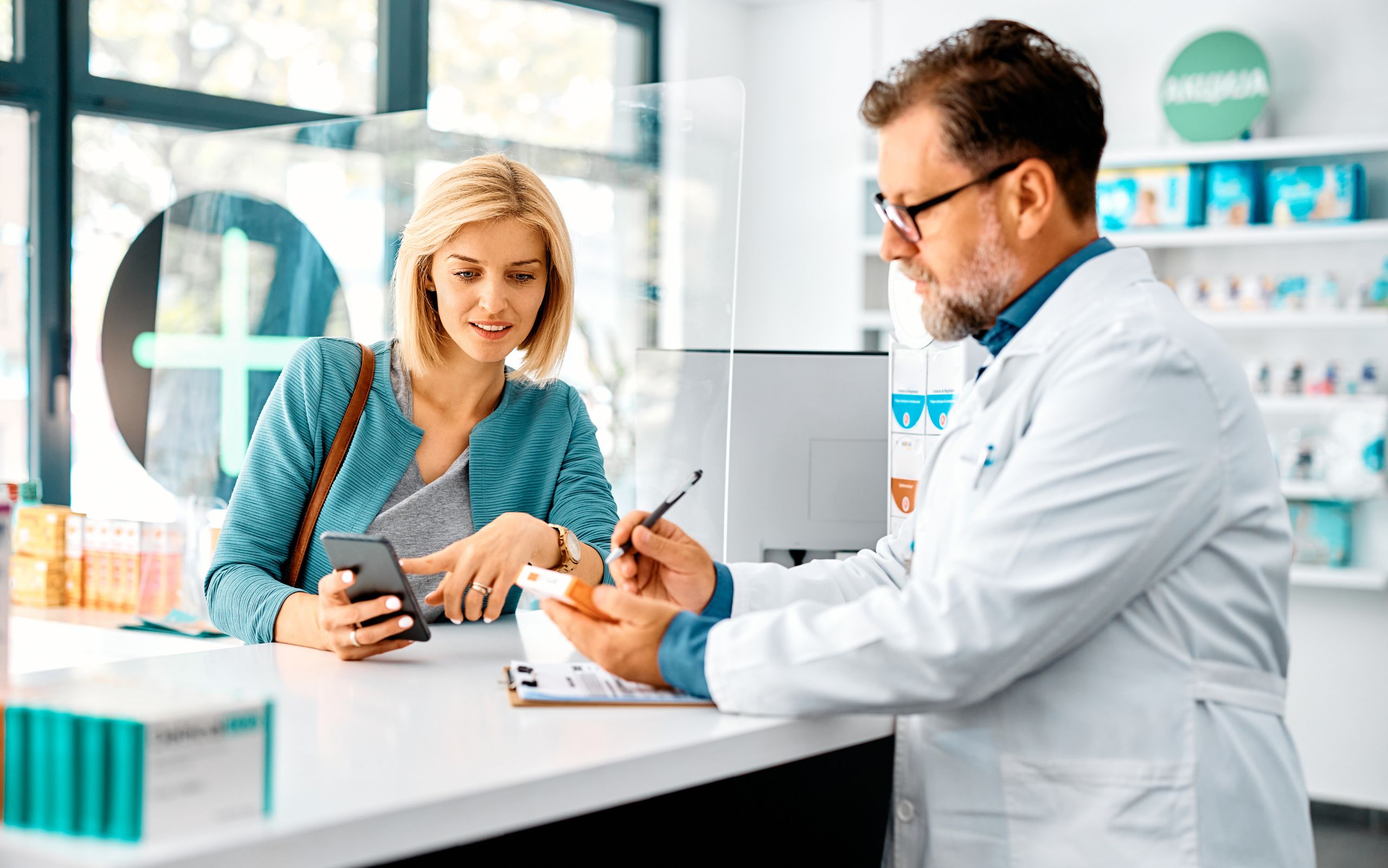 Pharmacist dispensing a medicinal cannabis prescription to a woman at a pharmacy 